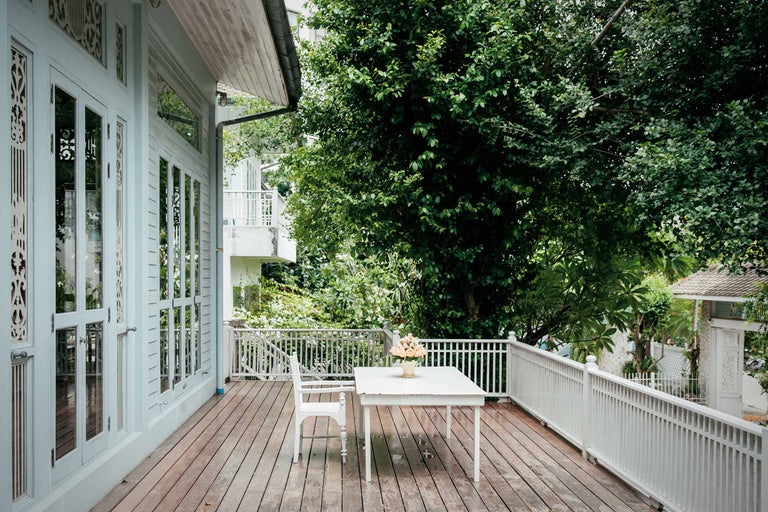 Veranda met houten vloer, tafel, stoel en reling