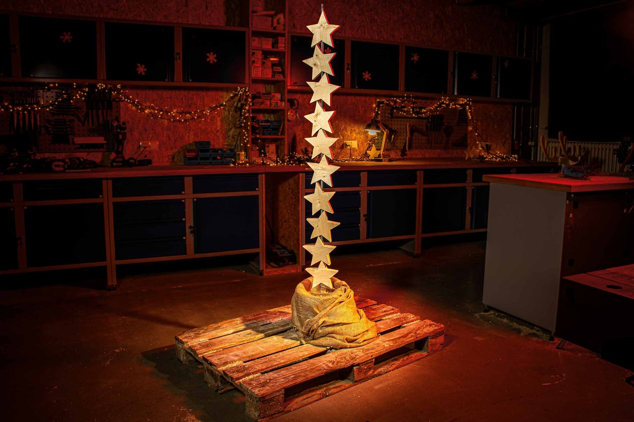 Werkplaatsdecoratie met houten sterren op een pallet en een lichtslinger op de achtergrond.