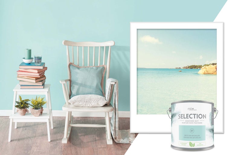 Decoratieve woonsfeer met een verfemmer, schommelstoel, wanddecoratie en bijzettafel