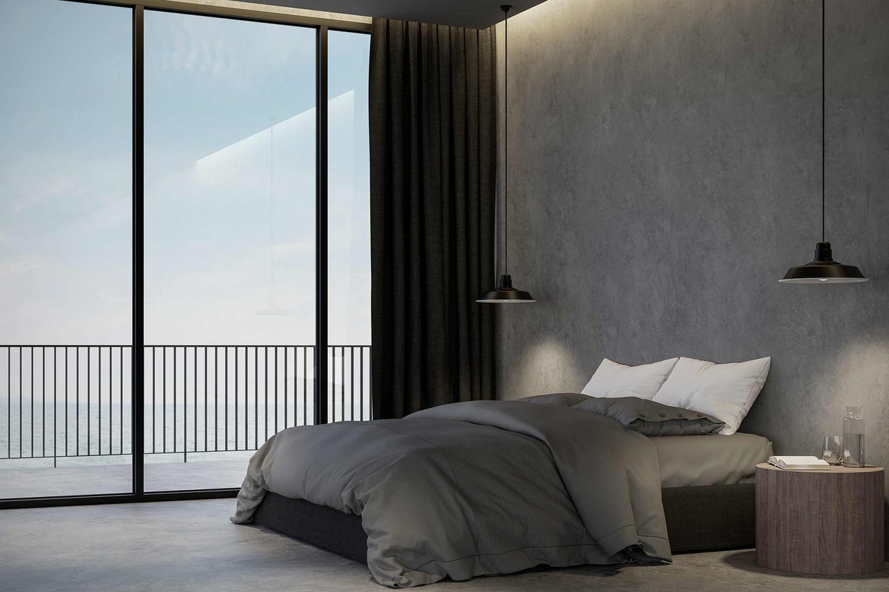 Moderne slaapkamer met bed, gordijnen en groot raam met uitzicht op zee