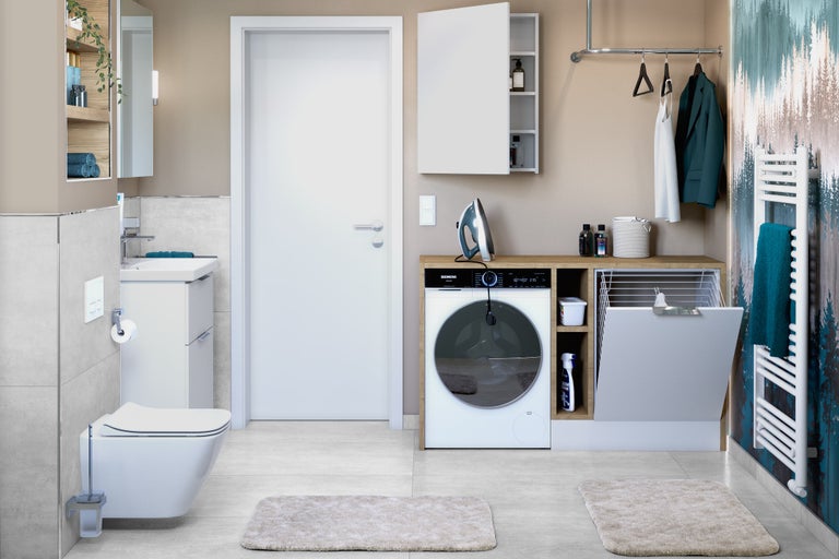Badkamer met wastafel, toilet, wasmachine, droger, radiator en opbergmogelijkheden voor een georganiseerde ruimte