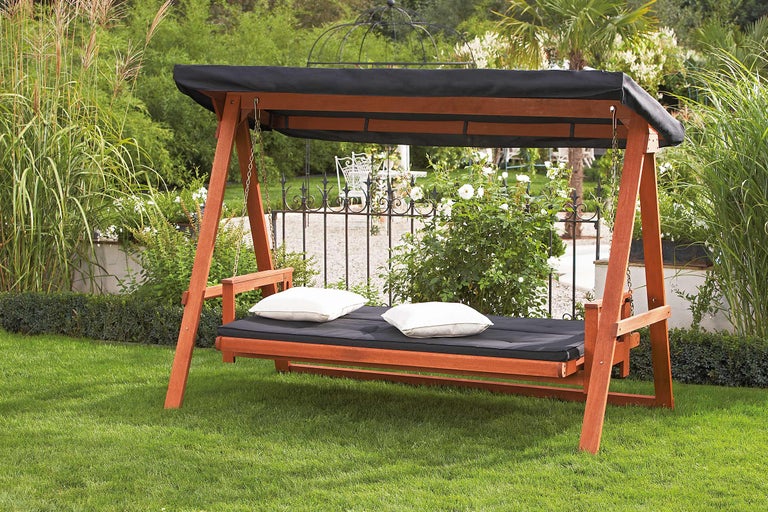 Houten tuinschommel met dak en kussens in de tuin