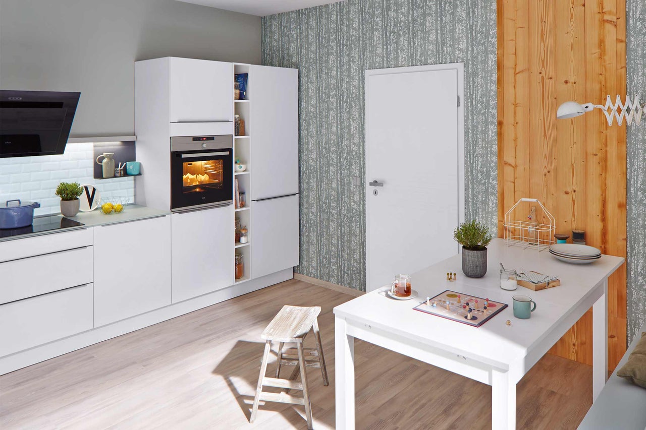 Lichte keukenruimte met witte meubels, eettafel en stoel.