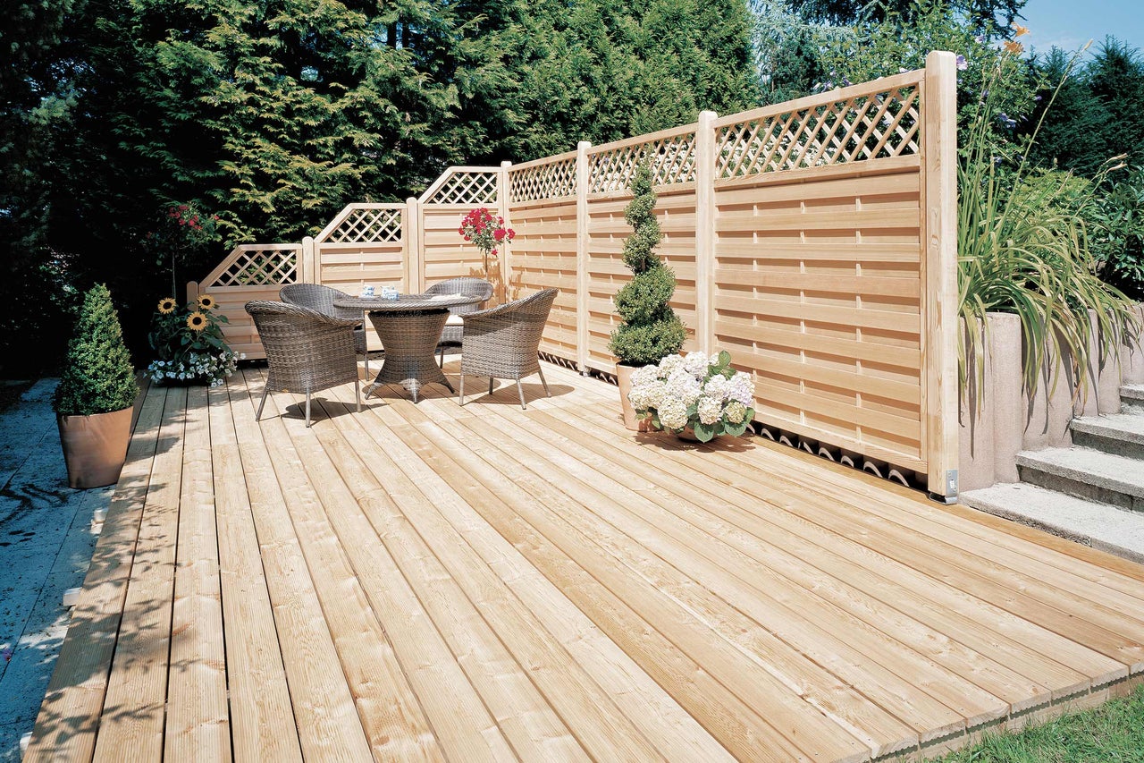 Houten terras met privacyscherm en tuinmeubelen in de tuin.