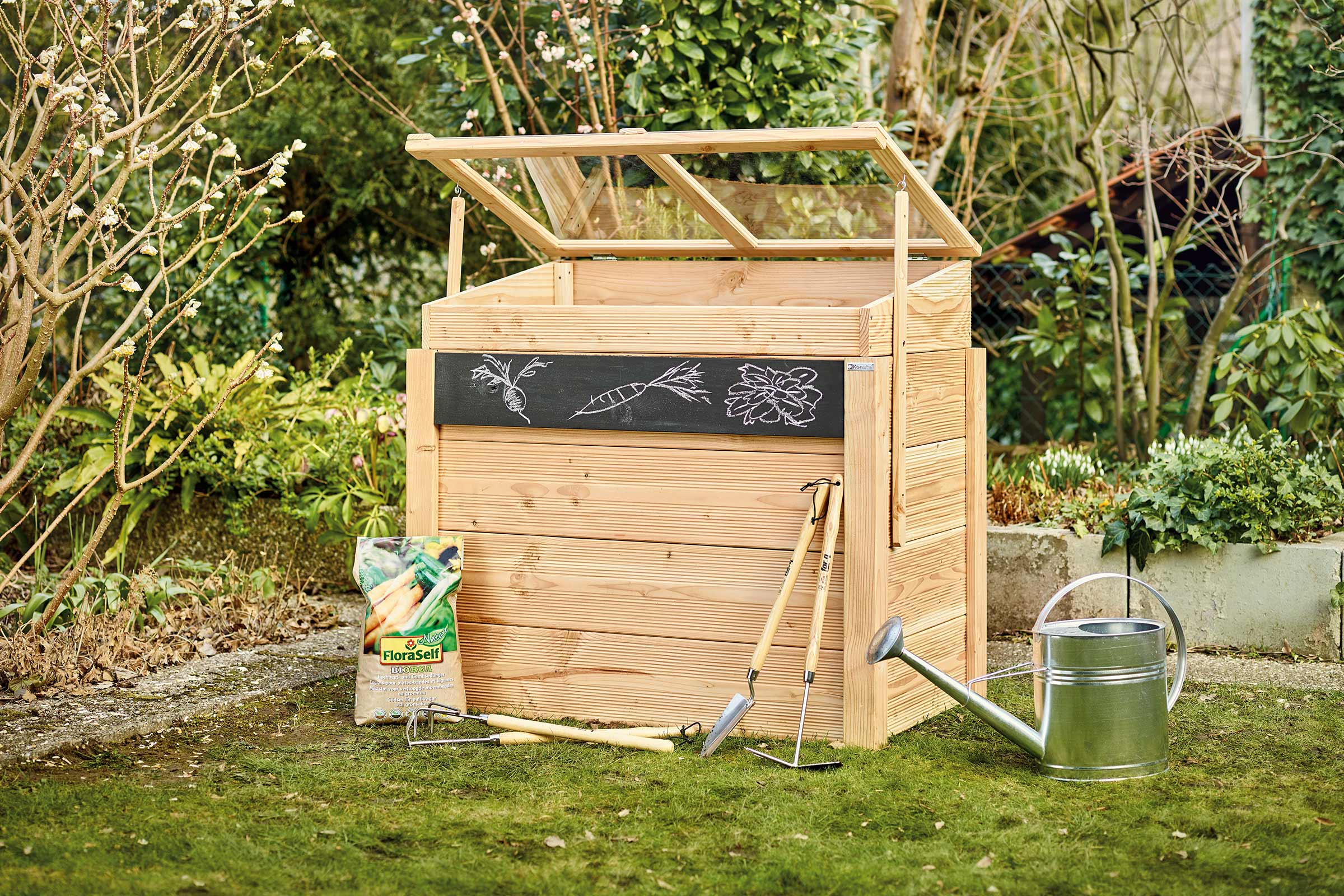 Houten plantenbak met open deksel, tuingereedschap en potgrond in de tuin