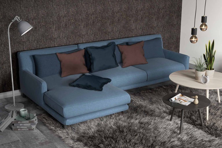 Woonkamer met hoekbank, kussens, vloerkleed en bijzettafels.