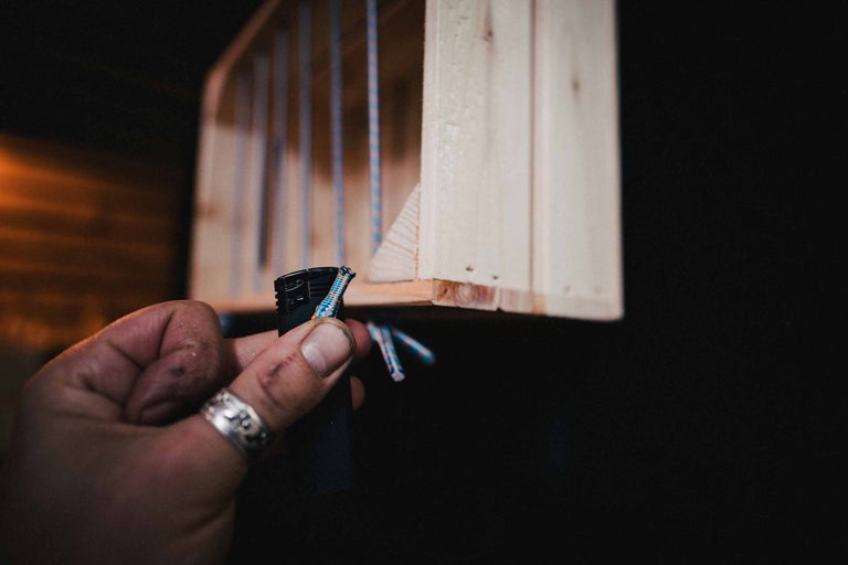 Een persoon gebruikt een aansteker om een touw aan een houten plank te bevestigen.