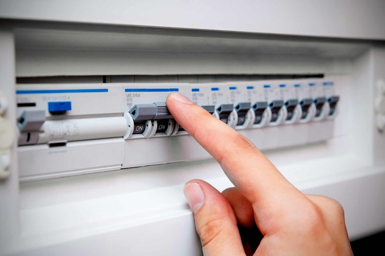 Een meterkast met een hand die een stroomonderbreker bedient