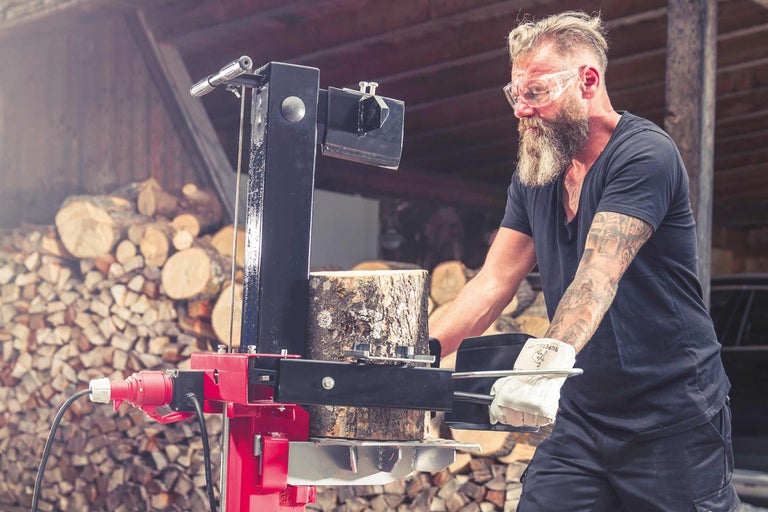 Man hakt hout met een houtklover in een lichte werkplaats