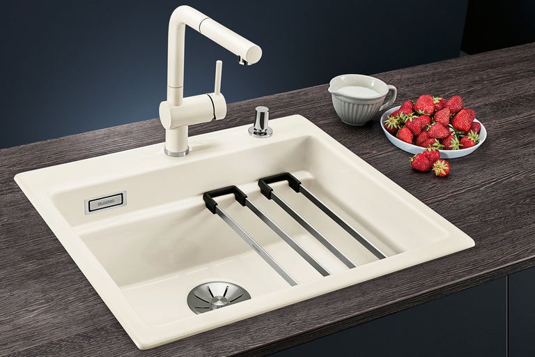 Spoelbak met afdruiprek, kraan, melk en aardbeien op een aanrecht