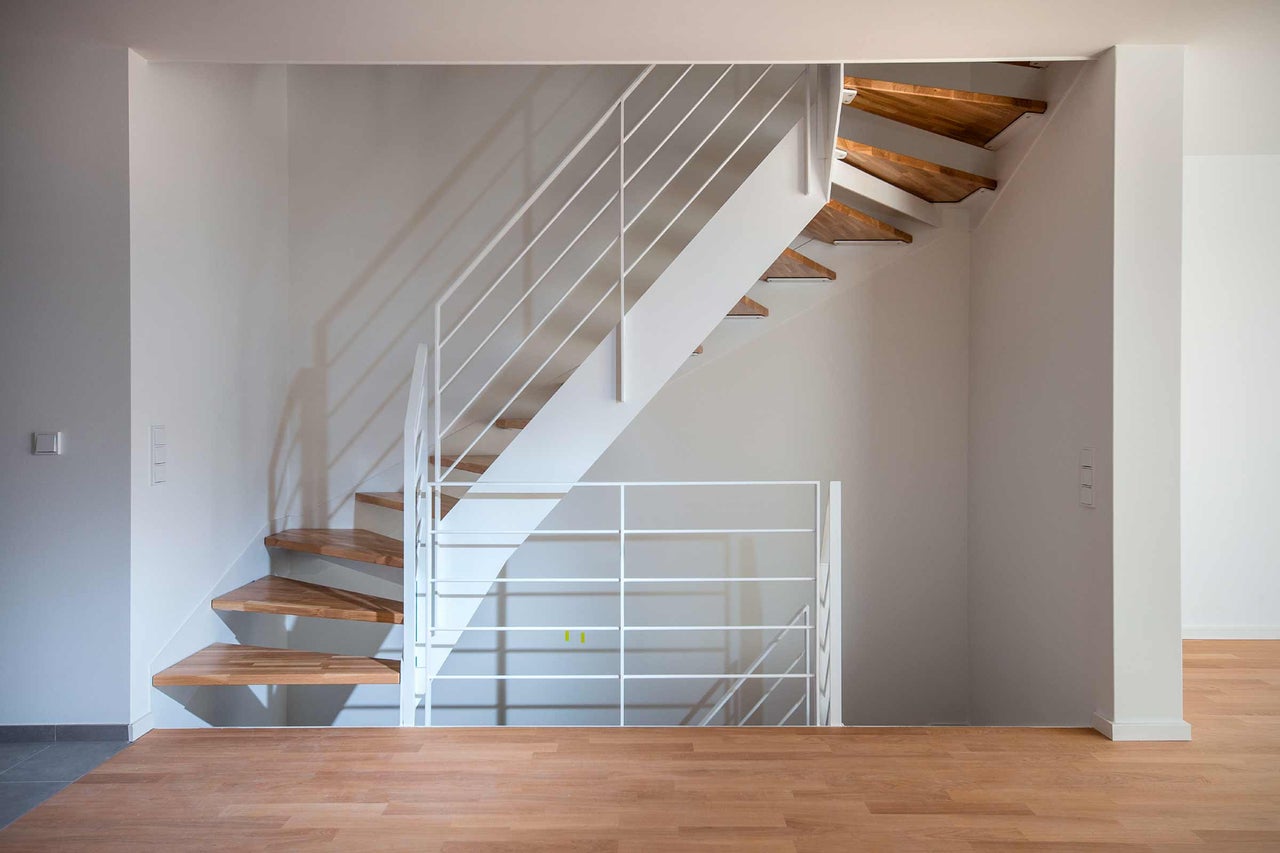Trap met houten treden en witte leuning in een lichte ruimte
