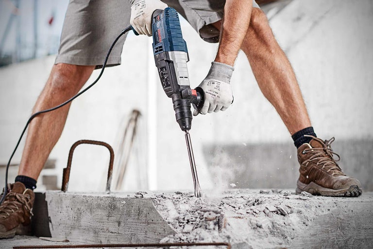 Een man werkt met een Bosch boorhamer aan beton.