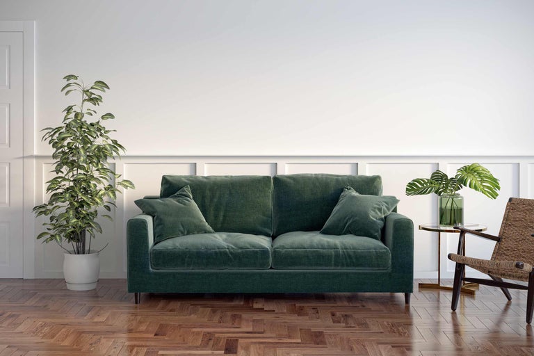 Gezellige woonkamer met groene bank, kamerplanten en houten vloer