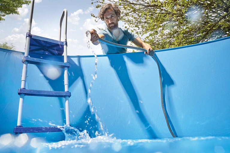 Man vult opzetzwembad met een waterslang en een ladder