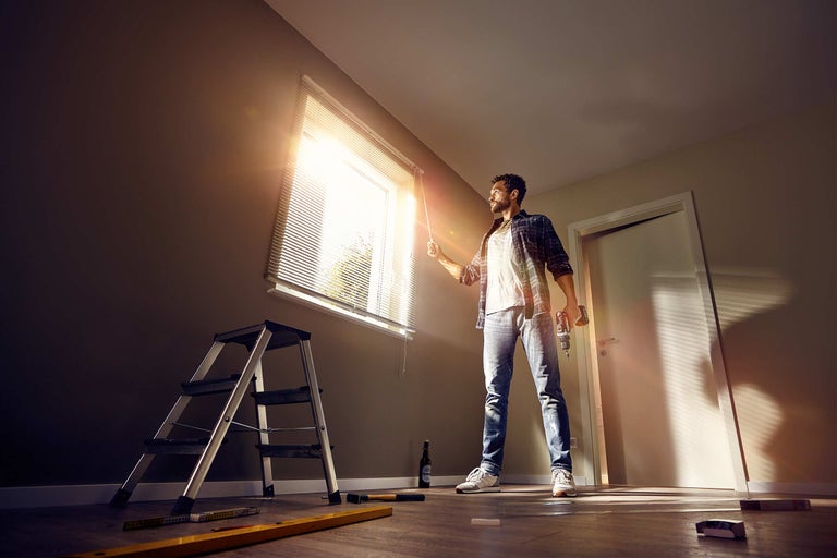 Man met boormachine regelt jaloezieën in een gerenoveerde kamer