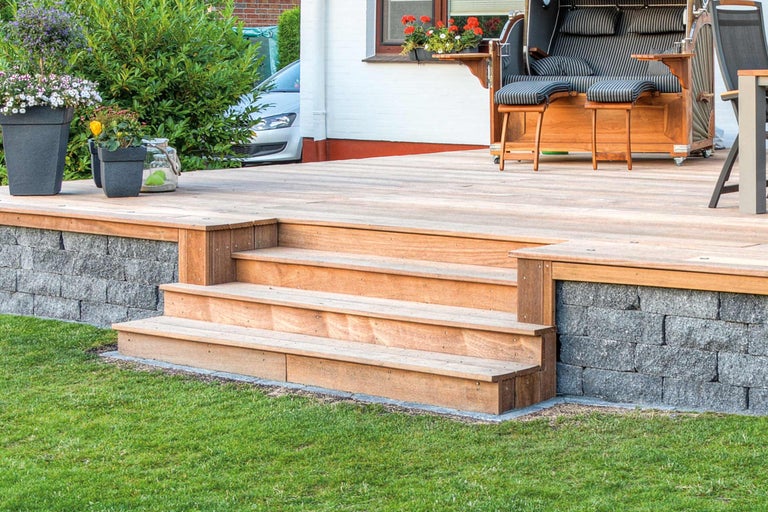 Terras met houten treden, muur en strandstoel in de tuin