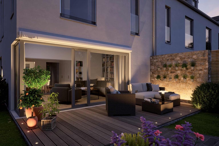 Verlicht terras met tuinmeubelen, planten en aangrenzend huis