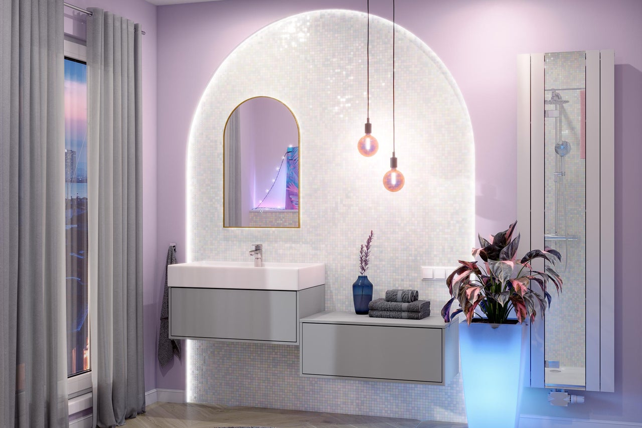 Moderne badkamer met grijs wastafelmeubel, witte wastafel, boogspiegel en verlichte mozaïekwand.