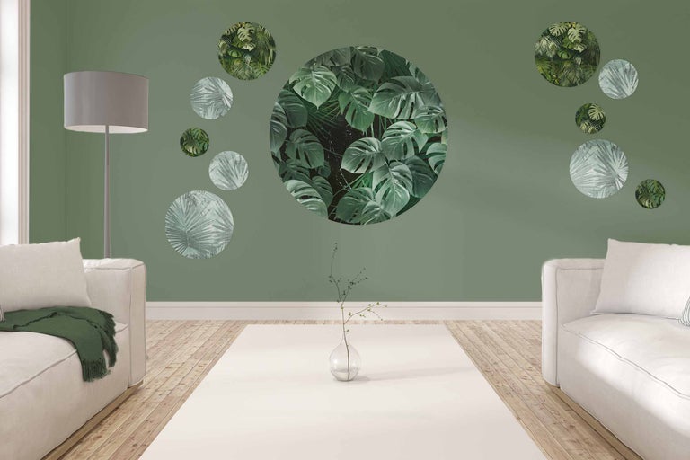 Woonkamer met banken, staande lamp en wanddecoratie met plantmotieven