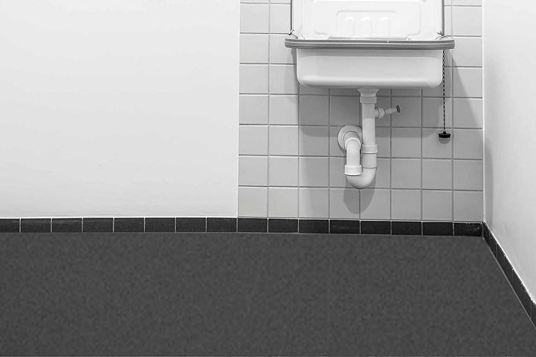 Wastafel met sifon en betegelde muur in de badkamer