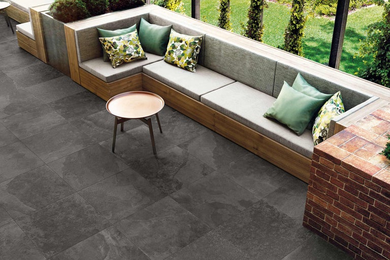 Buitenruimte met tegelvloer, zitplaatsen en tafel