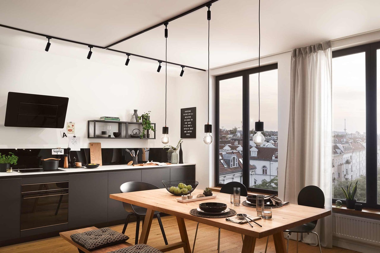 Lichte keuken met eettafel, keukenblok, hanglampen en spots voor plafondmontage.