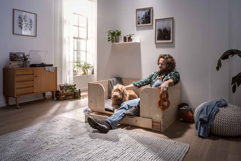 Lichte woonkamer met man en hond in een houten hondenbed met lade