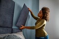 Vrouw bevestigt geluidspaneel aan de muur boven het bed Vrouw bevestigt geluidspaneel aan de muur boven het bed