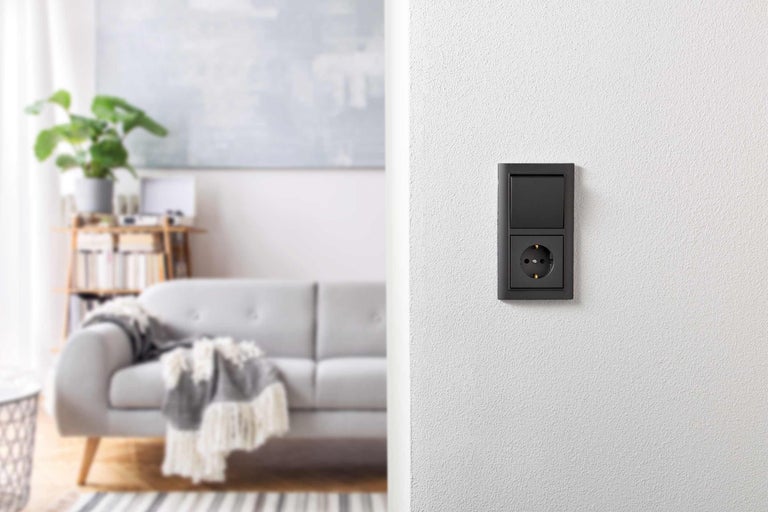 Schakelaar en stopcontact in een modern ingerichte woonkamer.