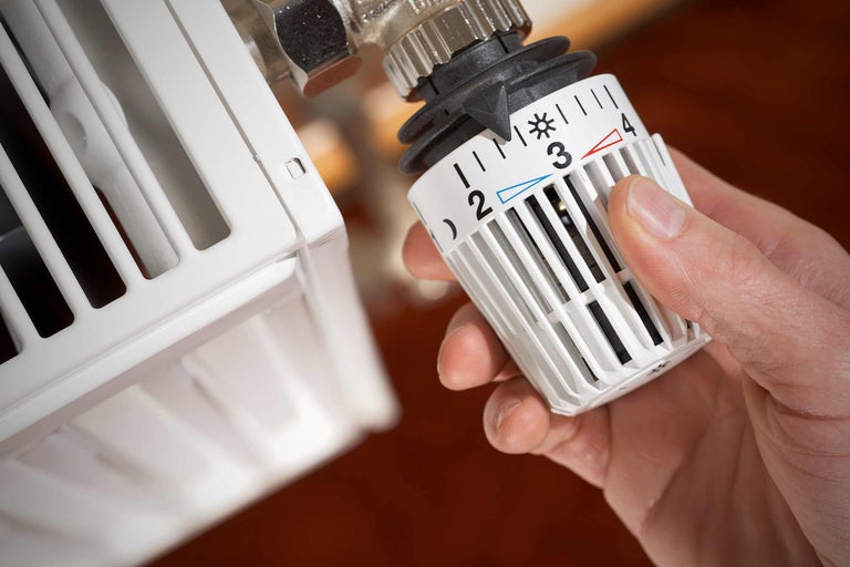 Close-up van een radiatorthermostaat die door een hand wordt aangepast