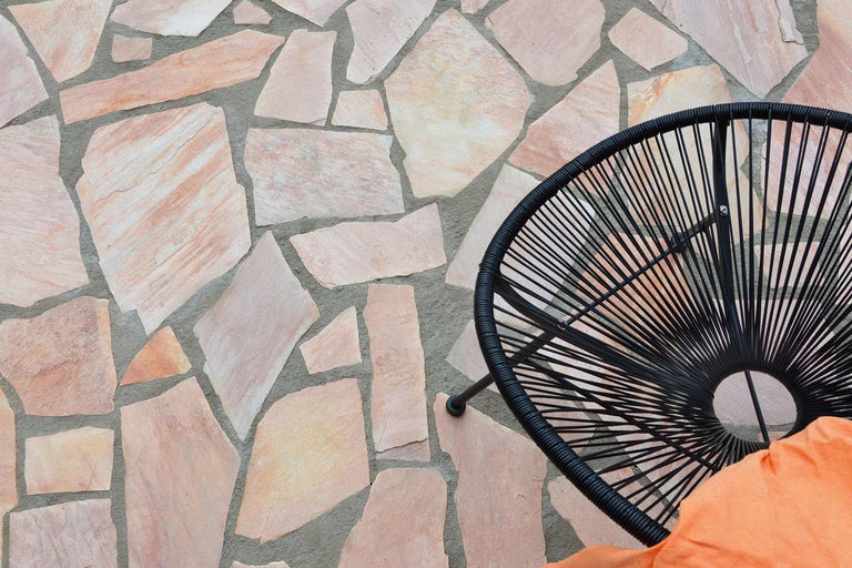 Terras met natuurstenen bestrating en een rotan stoel.