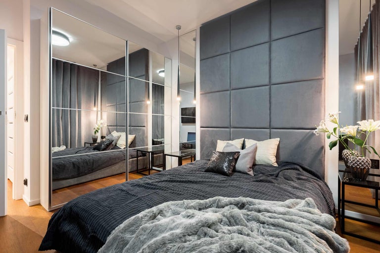 Moderne slaapkamer met bed, gestoffeerd hoofdeinde en spiegelkast