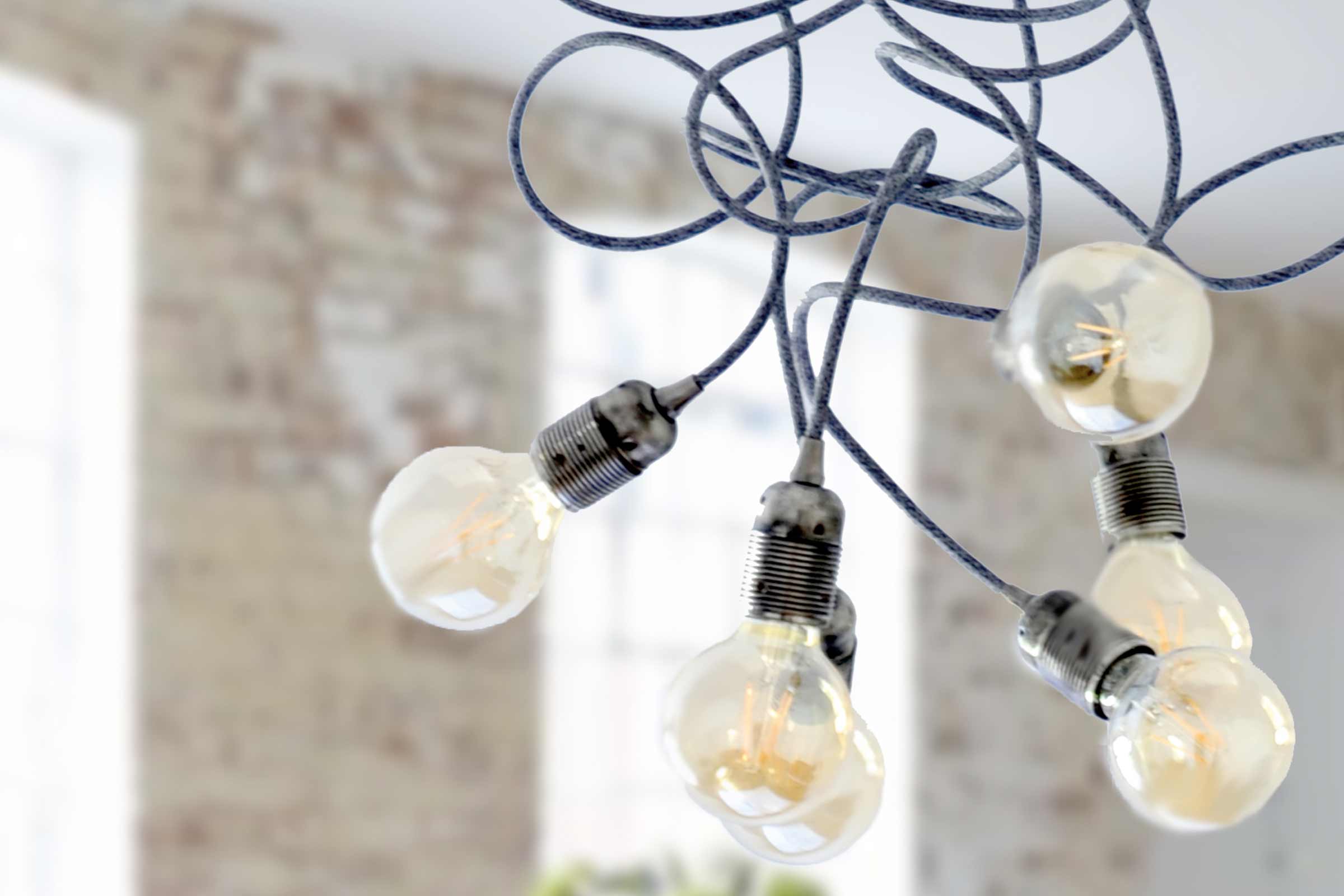 Decoratieve hanglamp met meerdere gloeilampen en textielkabels in een interieur