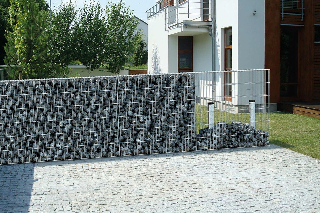 Schanskorfmuur gevuld met stenen in een tuinomgeving