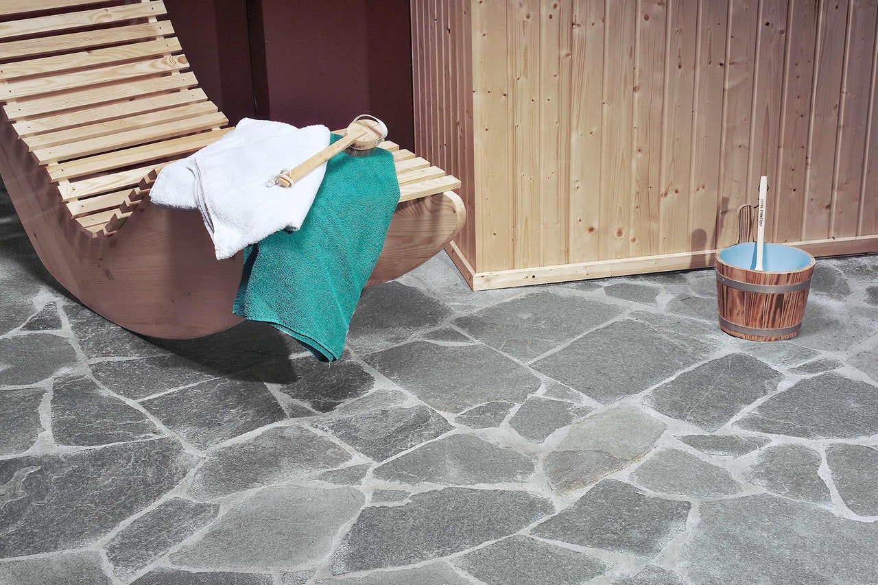 Sauna-interieur met ligstoel, handdoeken, emmer en stenen vloer