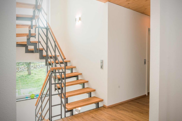 Trappenhuis met houten treden en metalen leuning in een lichte woonruimte