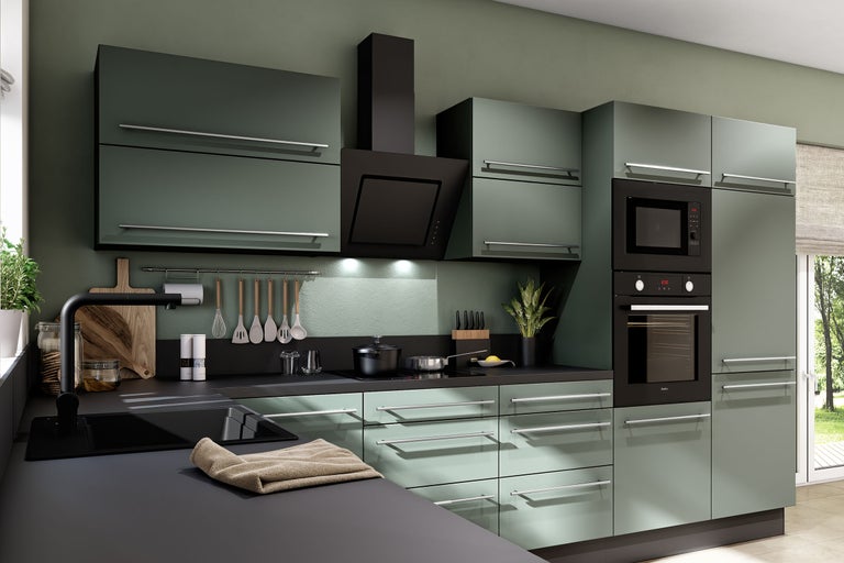 Moderne inbouwkeuken in matgroen met zwart werkblad, oven, magnetron, afzuigkap en zilverkleurige handgrepen.