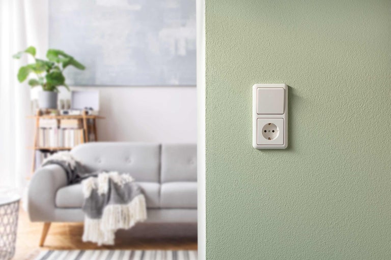 Schakelaar en stopcontact aan een muur in de woonkamer