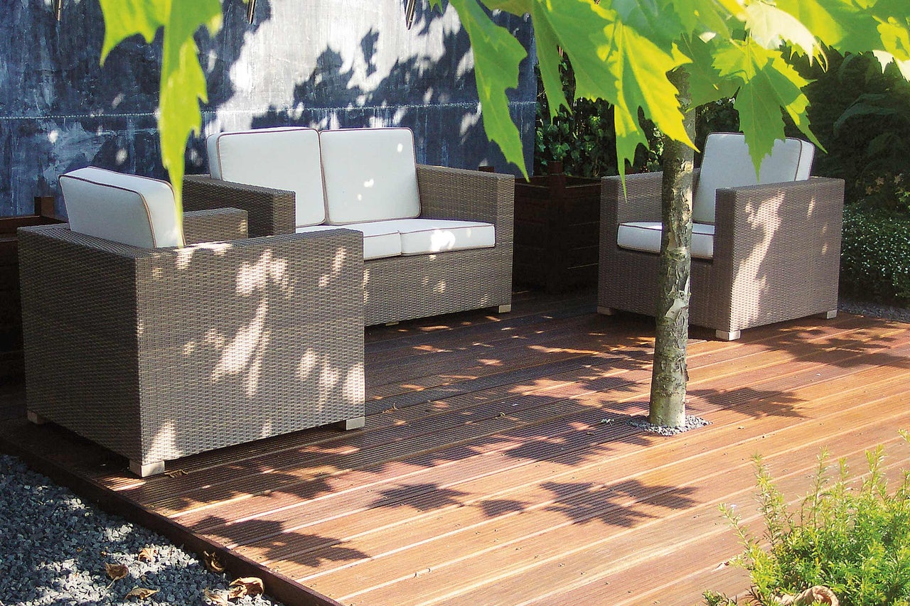 Tuinmeubelset van polyrotan met lichte kussens op houten terras