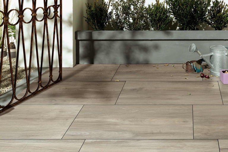 Terras met houten vloertegels, ijzeren hek en beplanting