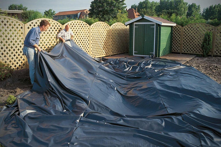 Twee mannen leggen vijverfolie in de tuin voor de vijveraanleg