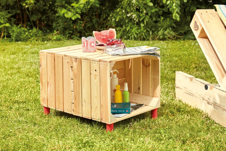 Tuinscene met een salontafel van houten kisten, drankjes en snacks op een gazon