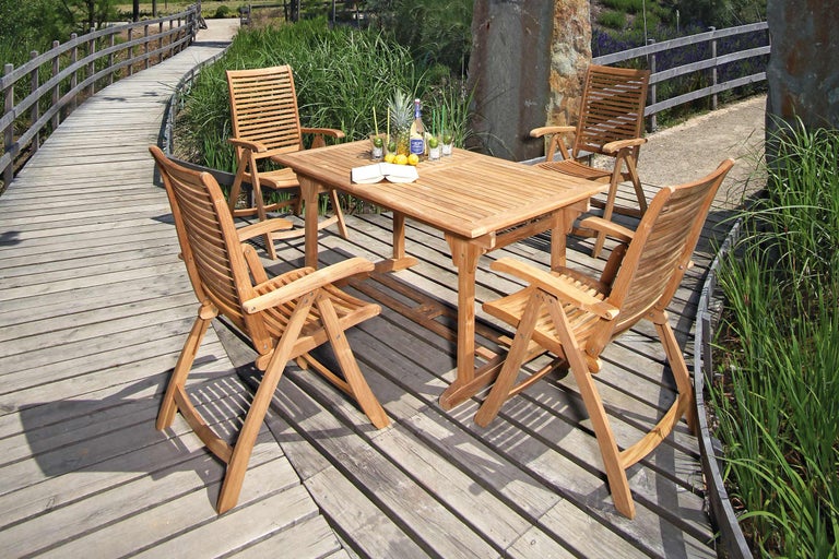 Tuinscene met teakhouten tafel en vier stoelen op houten terras
