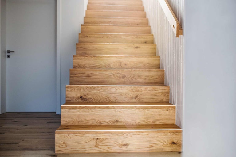 Houten trap in een heldere ruimte met aangrenzende deur