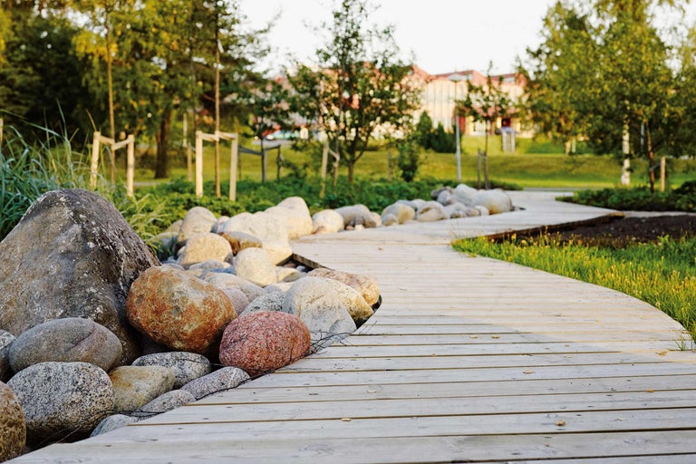 Houten looppad in de tuin met stenen en groen