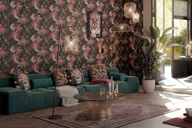 Woonkamer met groene bank, behang met motief en decoratieve elementen zoals kussens en lampen