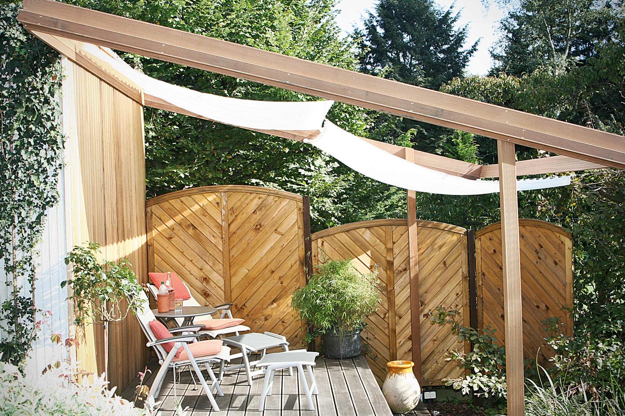 Zitgedeelte in tuin met houten terras, privacyscherm en zonnescherm