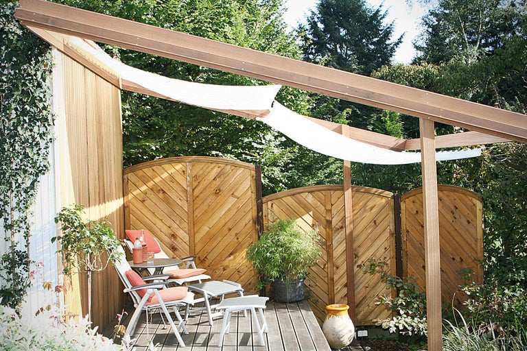 Zitgedeelte in tuin met houten terras, privacyscherm en zonnescherm