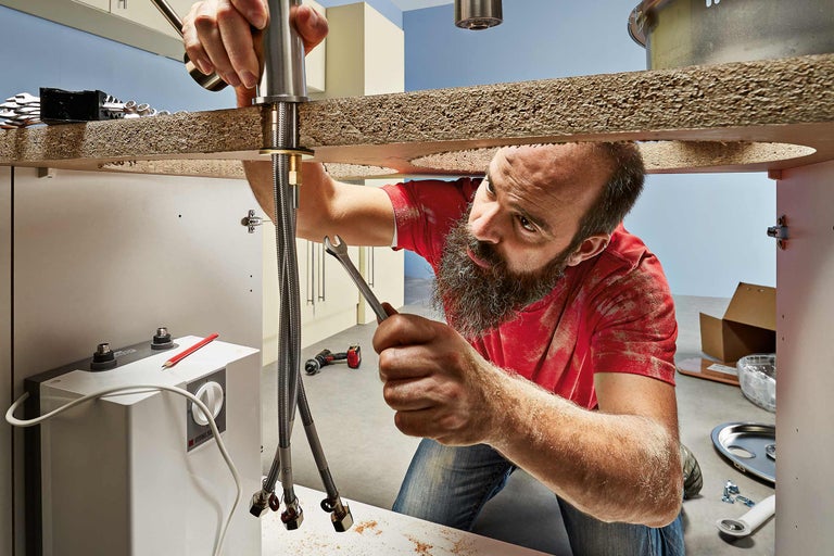 Een vakman installeert een kraan in een badkamer.