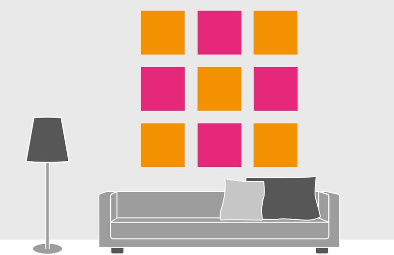 Woonkamer met bank, staande lamp en wanddecoratie met vierkante afbeeldingen